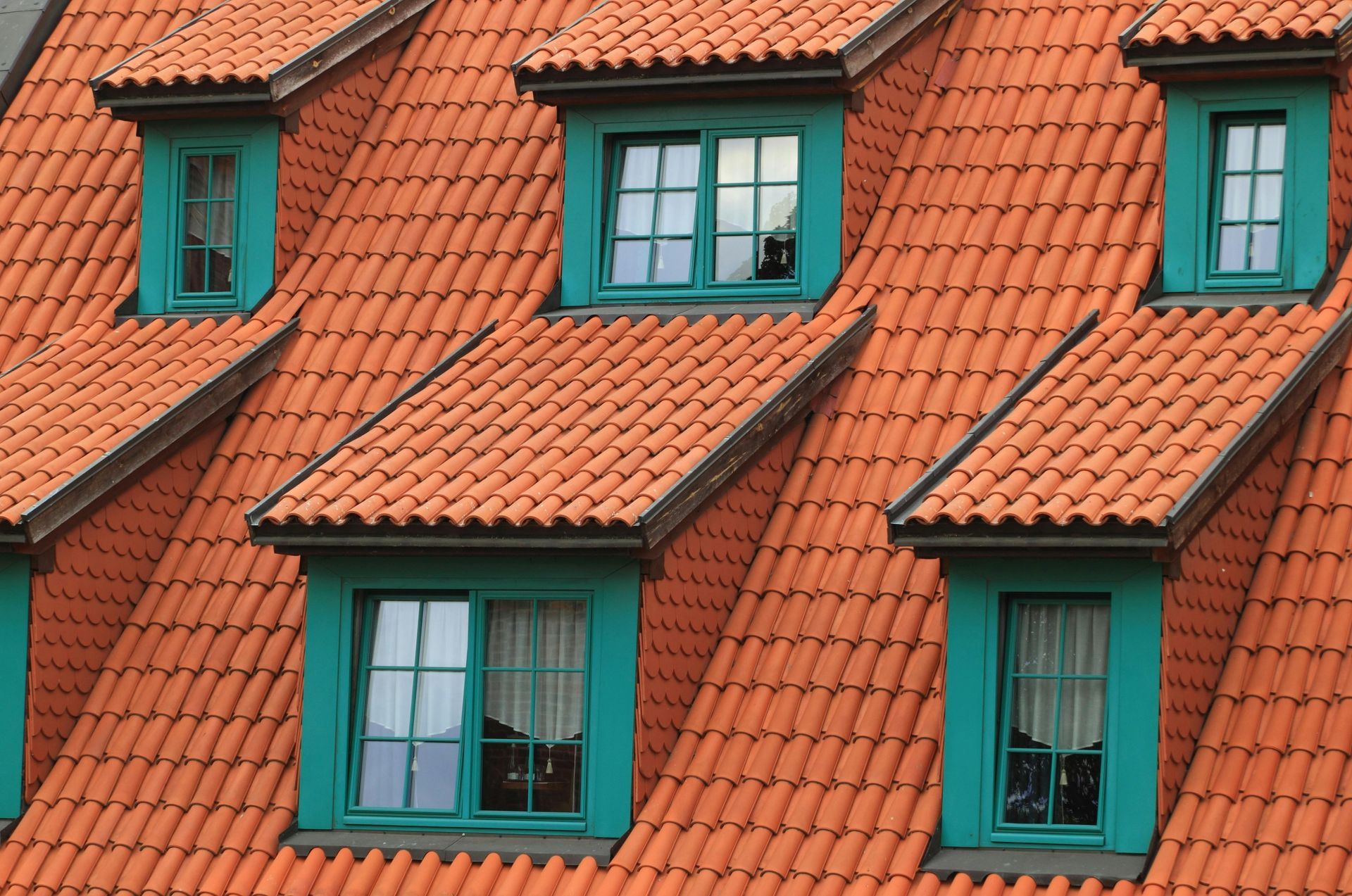 Red tile roof with teal window frames.